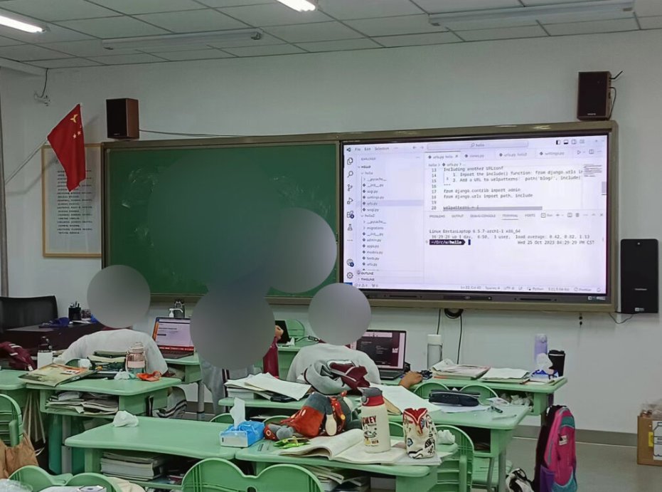 3 students in a classroom with a blackboard and a screen showing web development software up front. One student is tutoring another.