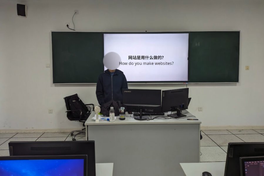 A student standing in front of the classroom before a screen showing the text: "How do you make websites?"